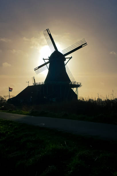 A classic windmill in Holland is silhouetted against the evening sky.