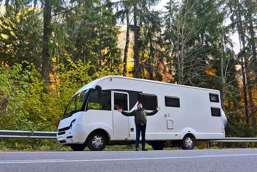 A man on the mountain road, in front of his camper van.