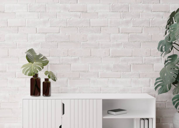 istock Empty, white brick wall. Mock up interior in contemporary style. Close up view. Free, copy space for your picture, text, or another design. Sideboard, monstera plants. 3D rendering. 1387128624