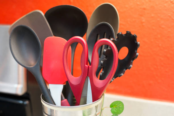 Cooking utensils sitting on counter in a domestic kitchen.  The container is a repurposed  vegetable can, adorned and sustainable.