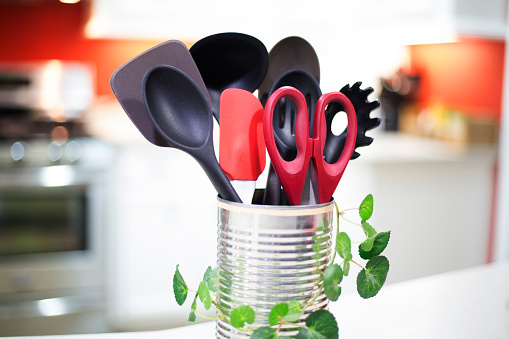 Cooking utensils sitting on counter in a domestic kitchen.  The container is a repurposed  vegetable can, adorned and sustainable.