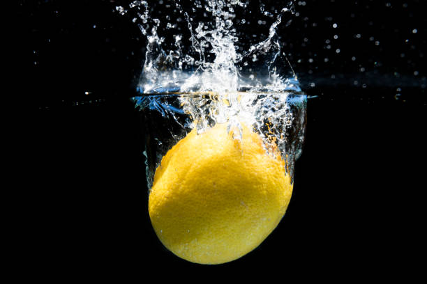 istock Lemon falling into the water and splashing drops on black background 1387130392