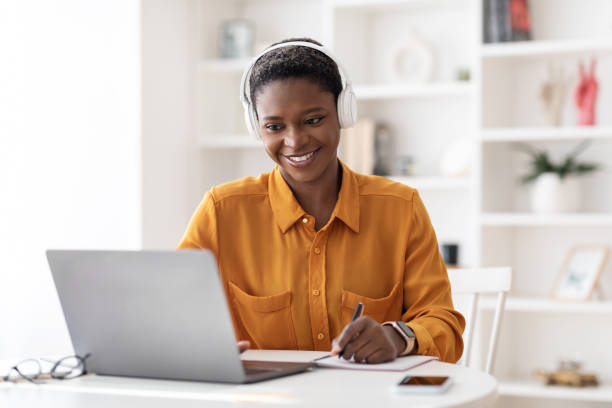 istock Cheerful black woman student having online class at home 1387131207