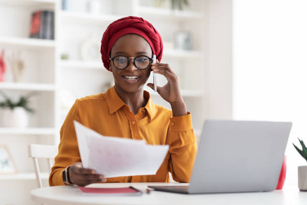 istock Black businesswoman working at office, having phone conversation 1387131335