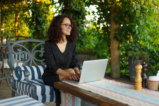 istock Portrait Of Smiling Woman Typing On Notebook While Working Online Using Laptop Computer. Female Sitting On Terrace. 1387132588