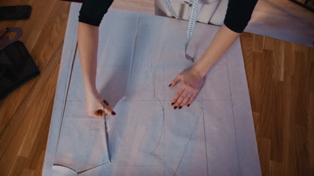 SLO MO Female tailor cuts the outlines of the future fabric product