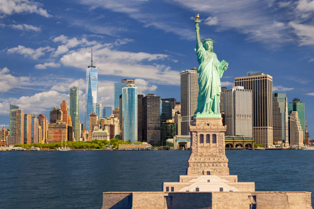 Statue of Liberty and New York City Skyline with Manhattan Financial District, World Trade Center, Blue Sky and Water of New York Harbor. stock photo