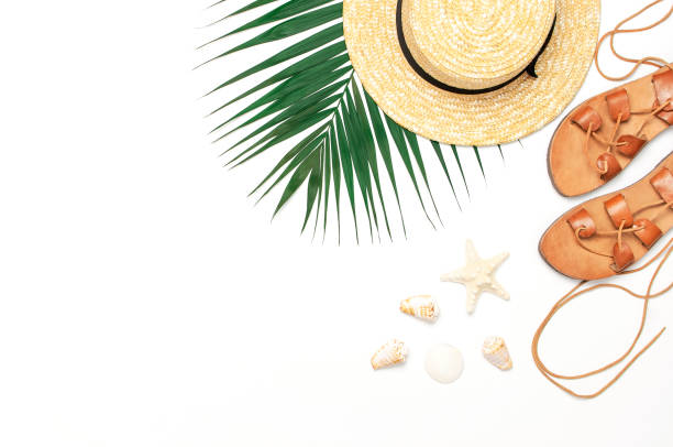 istock Woman's beach accessories flat lay. Straw hat, leather sandals, tropical palm leaves, seashells, starfish on white background. Top view copy space. Summer backdrop 1387134628