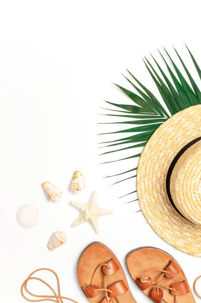 istock Woman's beach accessories flat lay. Straw hat, leather sandals, tropical palm leaves, seashells, starfish on white background. Top view copy space. Summer backdrop 1387134630