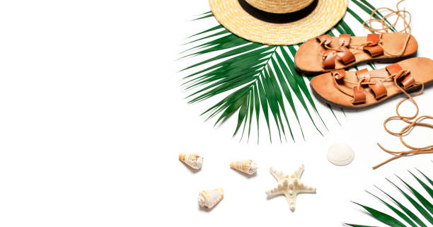 istock Woman's beach accessories flat lay. Straw hat, leather sandals, tropical palm leaves, seashells, starfish on white background. Top view copy space. Summer backdrop 1387134636