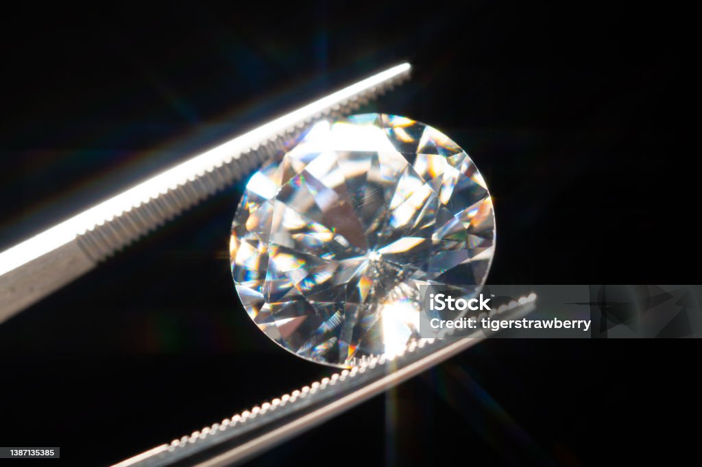 Diamond in tweezers selective focus, inspection and analyzing of brilliant cut crystal polish quality. Jewellery professional hand making in the studio. Macro shot, shallow depth of view. Diamond - Gemstone Stock Photo