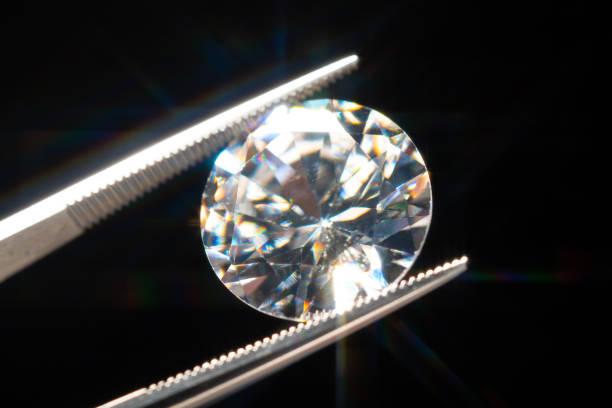 Diamond in tweezers selective focus, inspection and analyzing of brilliant cut crystal polish quality. Jewellery professional hand making in the studio. Macro shot, shallow depth of view. stock photo