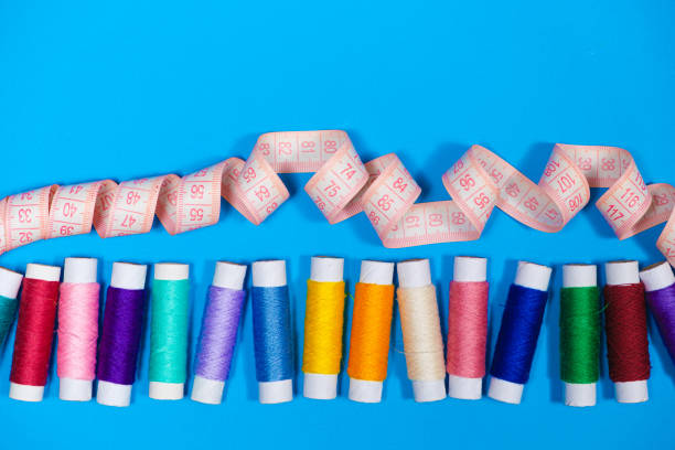 istock A set of multi-colored threads for sewing and a measuring tape on a blue background, top view. Tailoring and needlework equipment, tailor banner. 1387135636