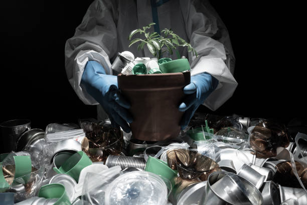 Environmentalist in protective suit holding young seedling in pot full of plastic dirt trash. Concept and symbol of catastrophic apocalypse, eco sustainability, growth care, protecting the earth. ambientalista con traje protector que sostiene plándalas jóvenes en maceta llena de basura de plástico. concepto y símbolo del apocalipsis catastrófico, la sostenibilidad ecológica, el cuidado del crecimiento, la protección de la tierra.
