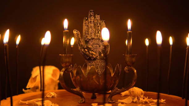 istock Magic and occult attributes on the table, pagan magic symbols background. Blowing black witchcraft candles. Spiritual mood and witch craft with mystic fantasy background and smoke. 1387135824