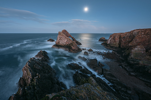 Stunning view of the sea cliffs by moonlight on the northern Scottish coast. Famous rock formation on the Moray Coast, Bow Fiddle Rock. Scottish Highlands, Scotland