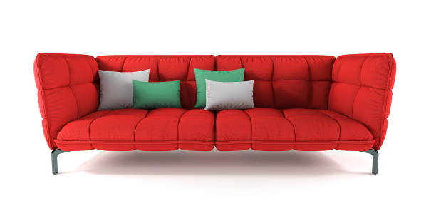 Modern red quilted fabric sofa on metal legs with pillows on isolated white background. Furniture, interior object. Bright scarlet sofa.