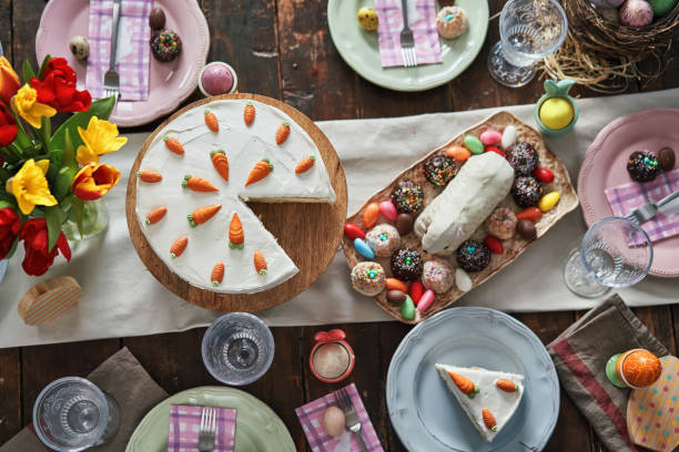 colorful decorated easter table with easter eggs, flowers and easter cake - paastaart stockfoto's en -beelden