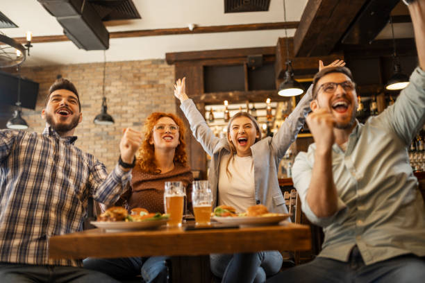istock Young people watching soccer game in pub cheering during goal 1387140654
