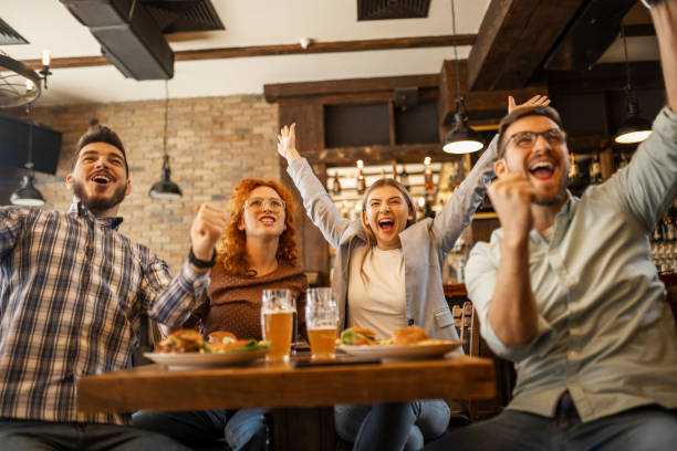 jovens assistindo jogo de futebol em pub torcendo durante o gol - pub - fotografias e filmes do acervo