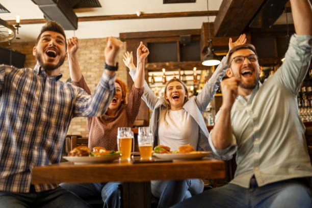 istock Young people watching soccer game in pub cheering 1387140672