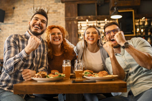istock Young people watching soccer game in pub cheering together 1387140681