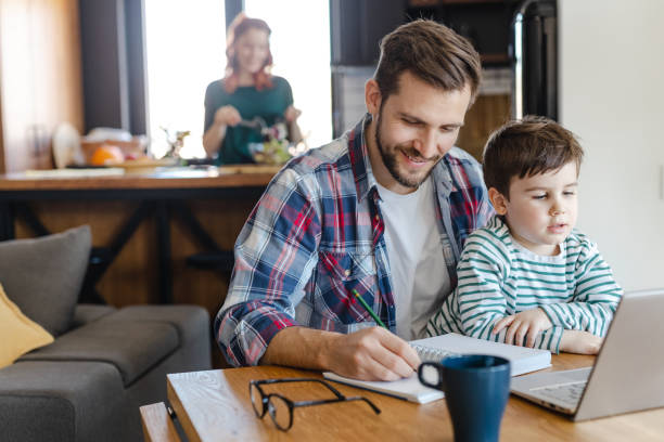 istock Father works on a laptop and holds his son on his lap 1387142242
