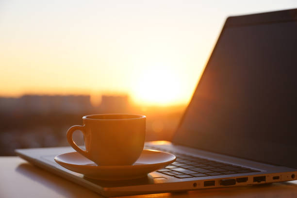 istock Coffee or tea cup on laptop against the window with sunshine 1387143229