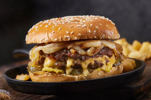 Two Thin Patties Stuffed with American Cheese and topped with Fried Onions,  Pickles and Fries