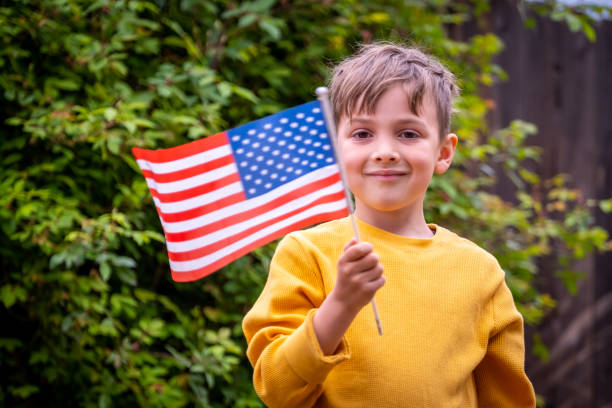 istock Smiling boy waving a US flag looking at the camera 1387144350