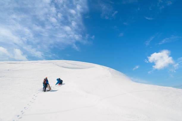 Elbrus, Russia - August 01, 2024: snowmobiles in the snow in the highlands against the background of a blue sky with white clouds