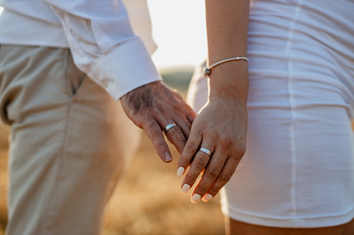 Married heterosexual couple in love, husband and wife with wedding rings in nature on a sunny summer day