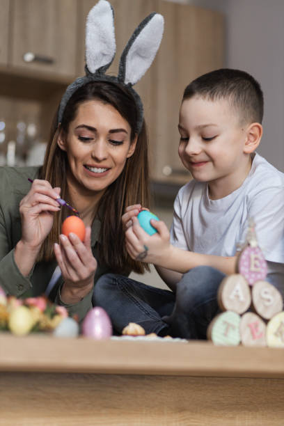 istock Cheerful mother and son painting Easter eggs 1387148186