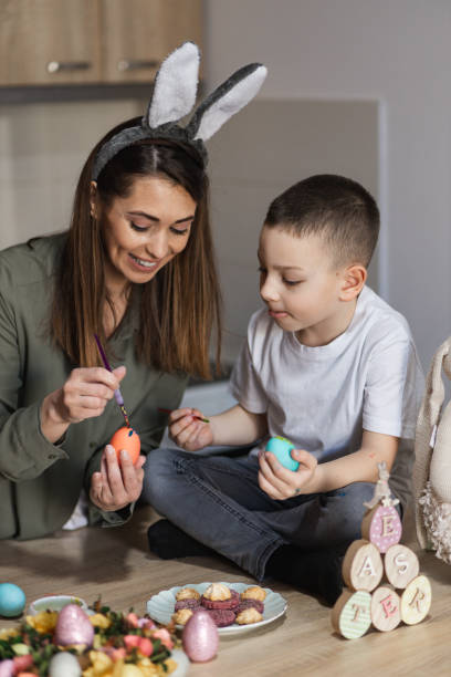 istock Cheerful mother and son painting Easter eggs 1387148330