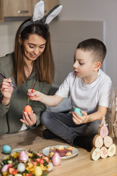 istock Cheerful mother and son painting Easter eggs 1387148338