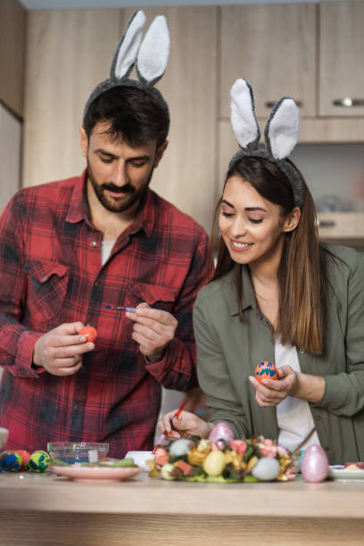 istock Attractive young couple painting Easter eggs wearing bunny ears 1387148494