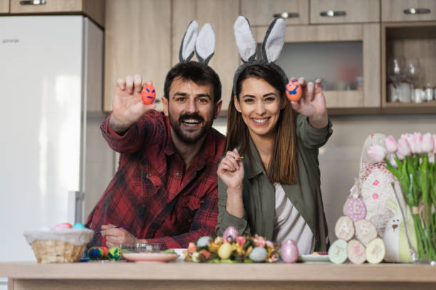 istock Attractive young couple holding Easter eggs wearing bunny ears 1387148552