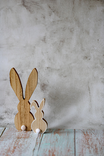Two wooden Easter bunnies on a light concrete background, Easter greeting card, copy cpace.