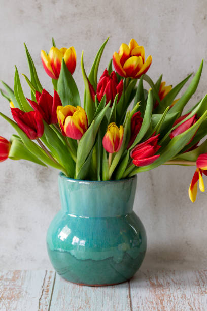 istock Turquoise ceramic vase with yellow-red tulips, copy space 1387149618