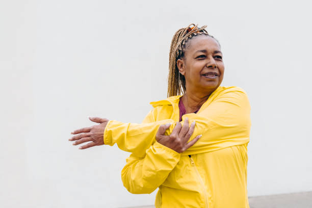 african senior woman doing workout routine while stretching outdoor - focus on face - exercício de relaxamento imagens e fotografias de stock