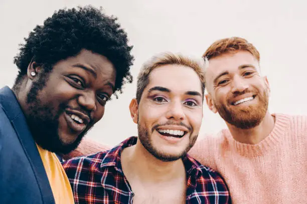 Diverse friends having fun together doing selfie outdoor - Focus on gay male face wearing makeup