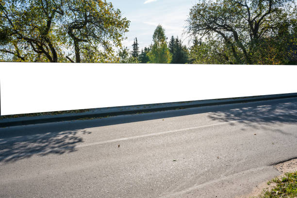 istock Long empty information signboard located on fence near asphalt road 1387149979