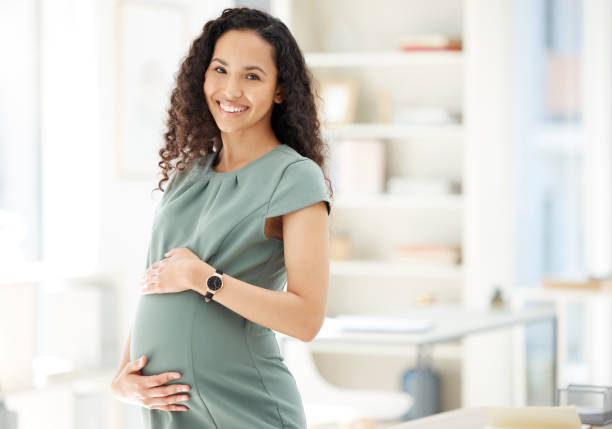 portrait d’une femme d’affaires enceinte debout dans un bureau - être enceinte photos et images de collection