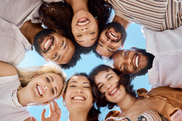 shot of a group of friends standing together in a huddle - group of people women beach community imagens e fotografias de stock