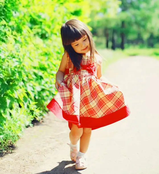 Portrait of little girl child outdoors walking in sunny summer park
