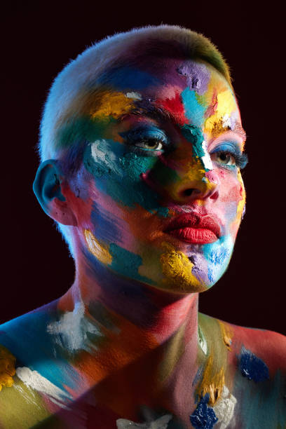 istock Studio shot of a young woman posing with multi-coloured paint on her face 1387152492