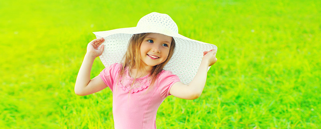Young girl in park with hat and backpack. Enjoying the sun looking happy.