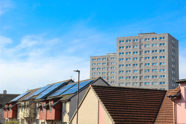 New Houses and High Rise Flats Newly built houses with solar panels on the roofs and high rise flats behind on blue sky and cloud background in Edinburgh Scotland council flat stock pictures, royalty-free photos & images