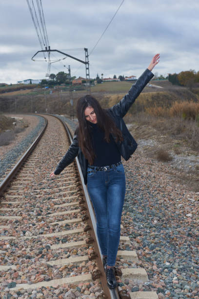 istock A girl in a black windbreaker balancing on train rails 1387156993