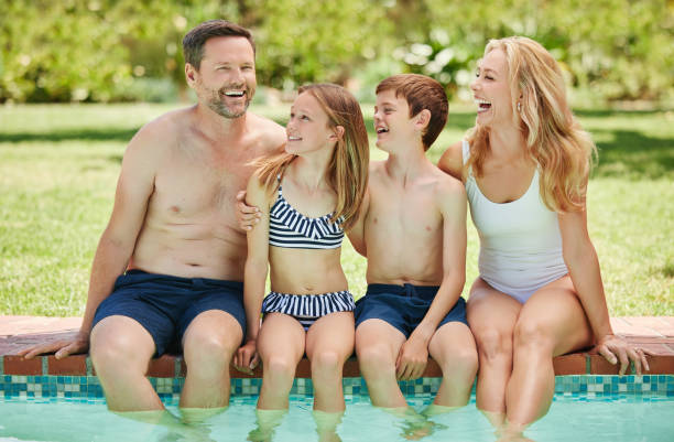 scatto di una coppia e dei loro due figli che trascorrono del tempo a bordo piscina - real estate immagine foto e immagini stock